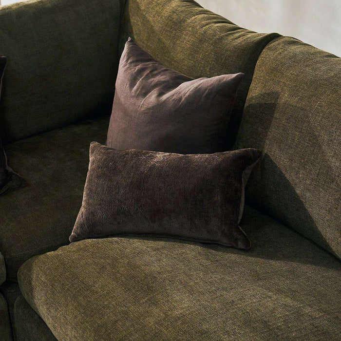 Two dark brown textured throw pillows resting on an olive green fabric sofa.