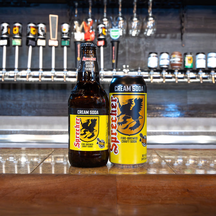 Two bottles of Sprecher Cream Soda on a bar counter with beer taps in the background.