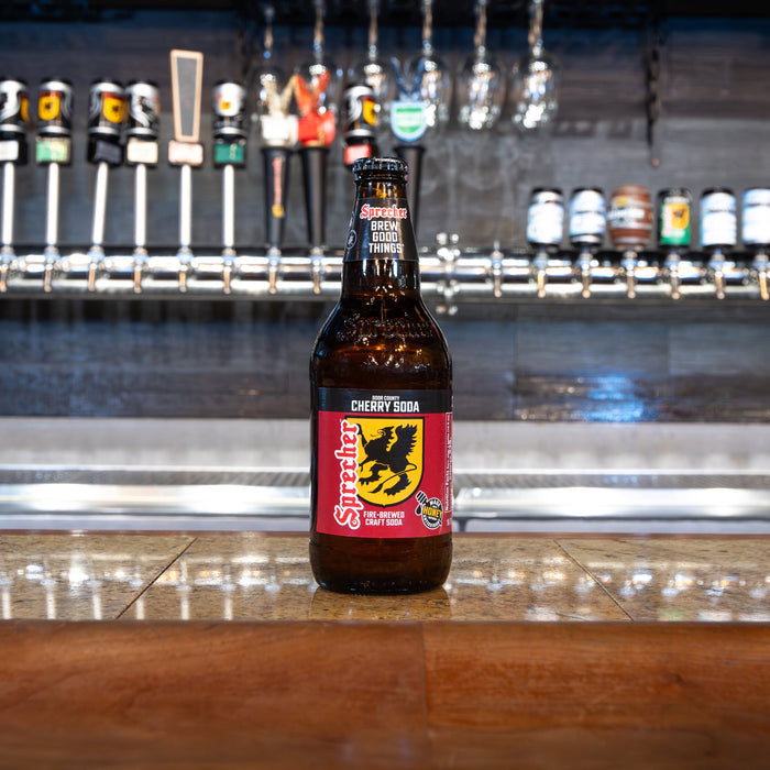 Bottle of cherry soda on a bar counter with beer taps in the background