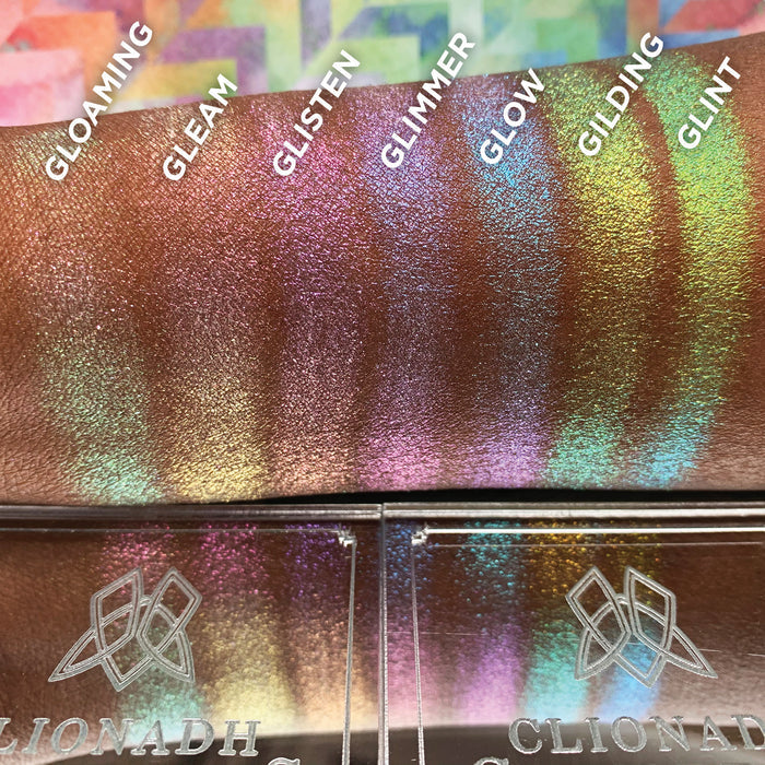 Straight angled arm swatches on deep skin tone of Gleam Glitter-Type Iridescent Multichrome Eyeshadow compared to Gloaming, Glisten, Glimmer, Glow, Gilding, Glint
