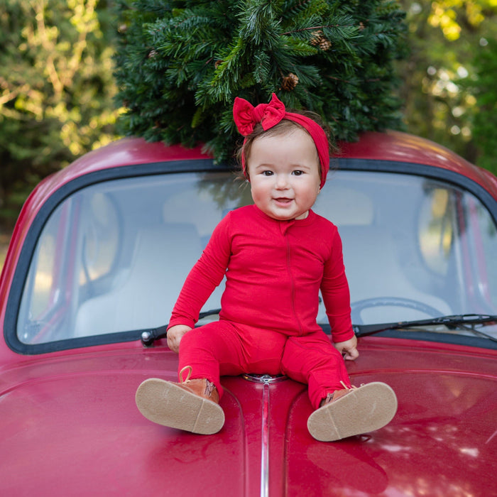 Infant wearing Kyte Baby Bow and Matching Romper in Cardinal Red