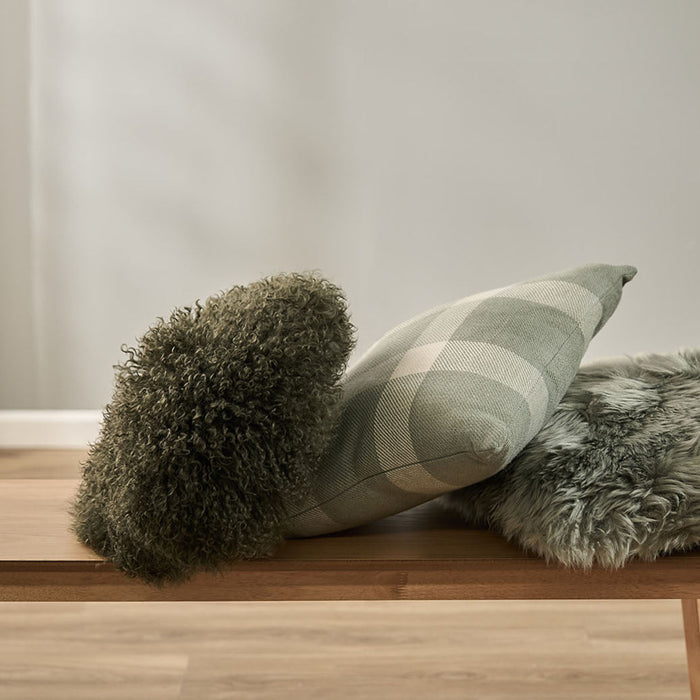 Lambie Cushion in Olive arranged in an assortment of other green cushions.