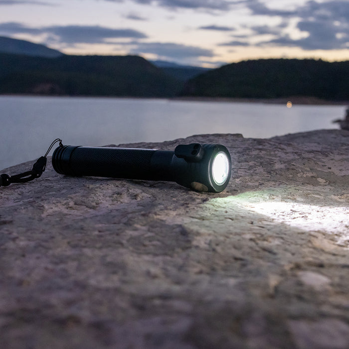 Flashlight on a rock with a lake and mountains in the background