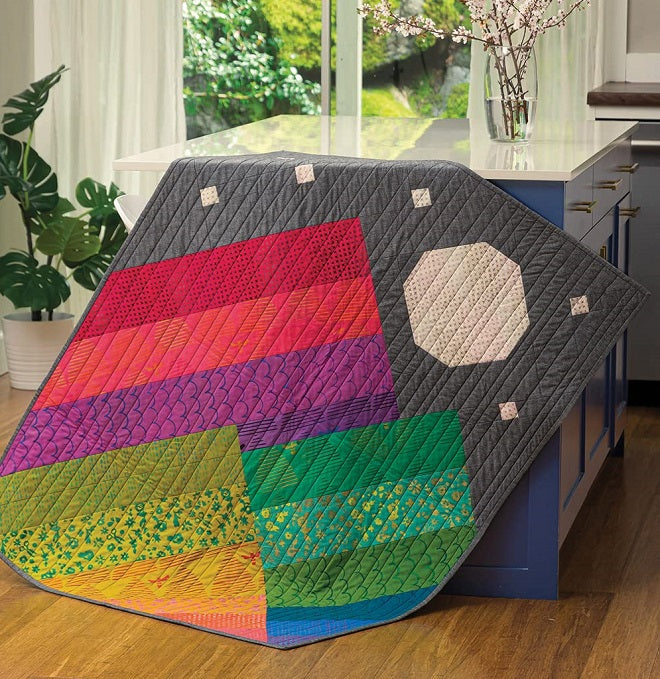 Colorful mountain and moon quilt hanging from a countertop