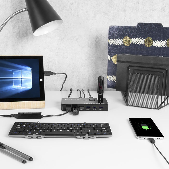 Plugable USB 3.0 10-Port Hub with SuperSpeed data transfer, connected to a tablet, flash drives, and a charging phone.
