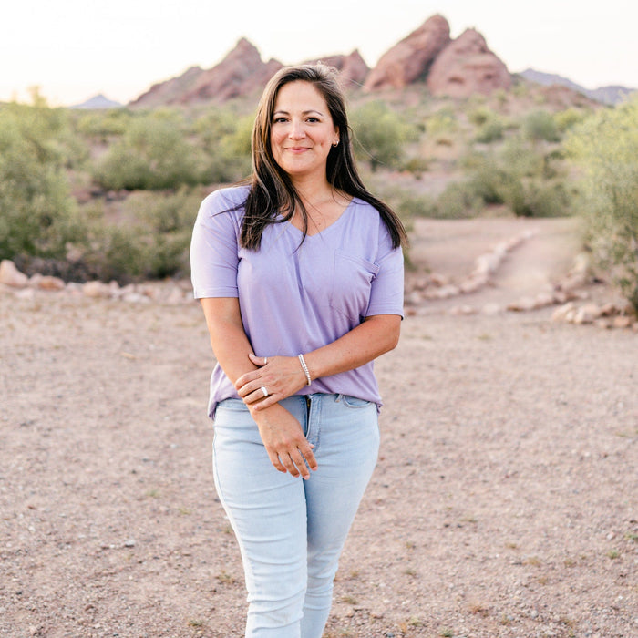 Female model standing in the desert wearing the Women’s Relaxed Fit V-Neck in Taro paired with light wash jeans