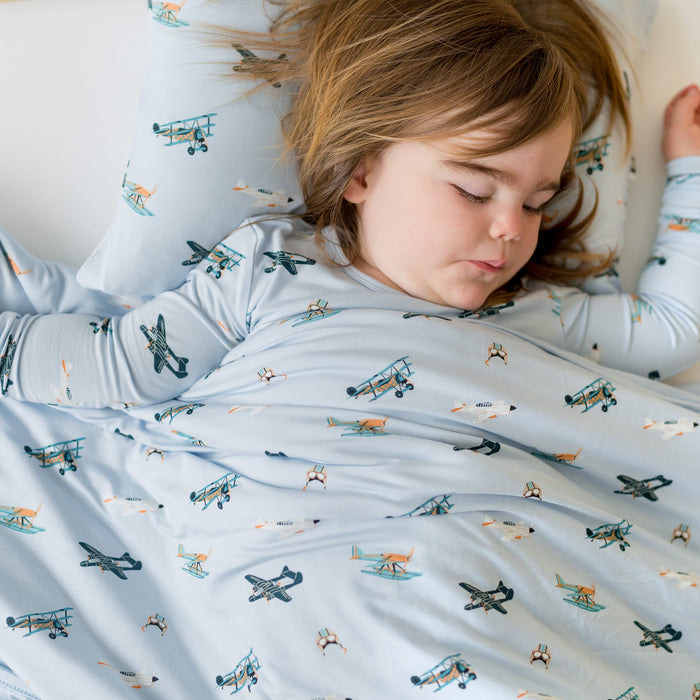 Close up of child sleeping in a bed with the Youth Blanket in Take Off 1.0 on top of them