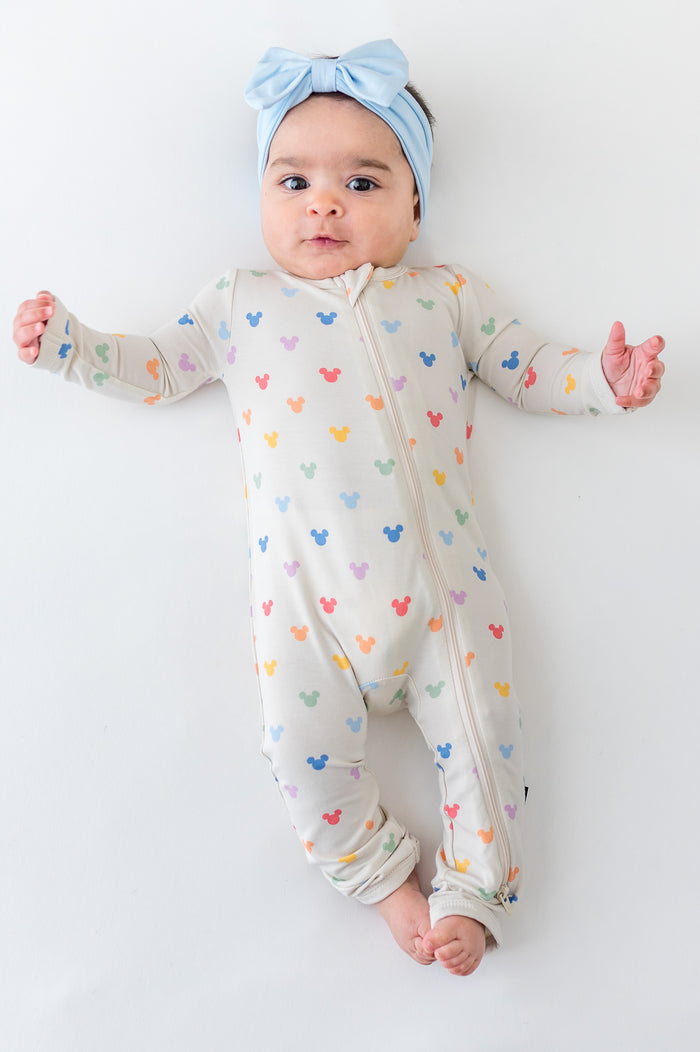 Baby in a colorful mickey head printed zippered romper and blue bow
